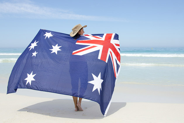 Ten things to take on an Australia cruise (Photo: Rob Bayer/Shutterstock) woman wearing akubra hat and with Australian flag around shoulder standing at tropical Australian beach