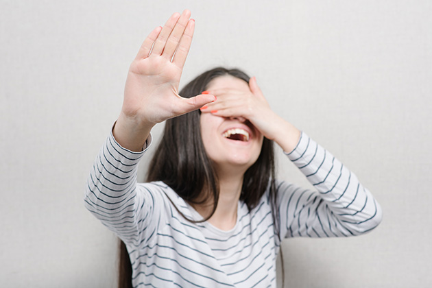 Position Yourself Strategically (Photo: file404/ Shutterstock) girl covers her face for photographer, camera