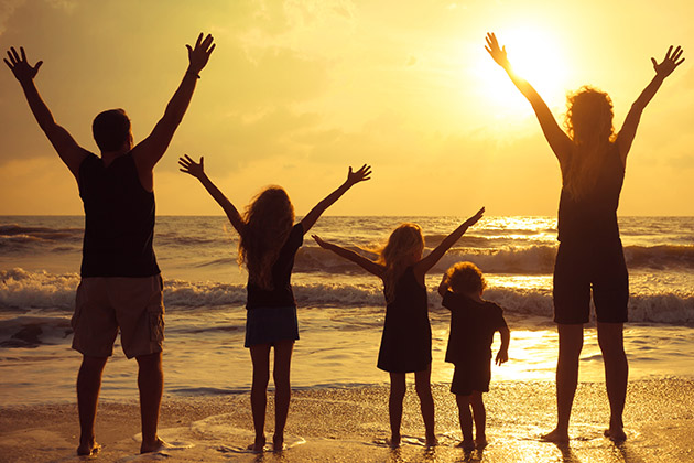 Bring the Gang (Photo: altanaka/Shutterstock) Happy family standing on the beach at sunset