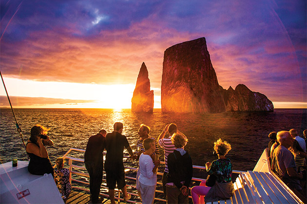 Kicker Rock in the Galapagos (Photo: Lindblad Expeditions) Lindblad passengers looking out towards the towering Kicker Rock at sunset, from a Lindblad expedition cruise deck