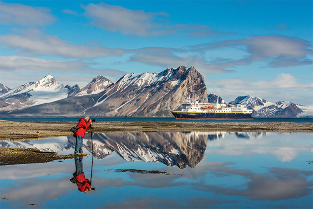 National Geographic Explorer passenger photographing Goose Bay in Norway (Photo: Lindblad Expeditions) Shot of a National Geographic Explorer passenger photographing Goose Bay in Norway with the ship in the background