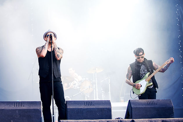 Good Charlotte in Concert. Lia Koltyrina/Shutterstock Two band members playing on stage with bright lights in background