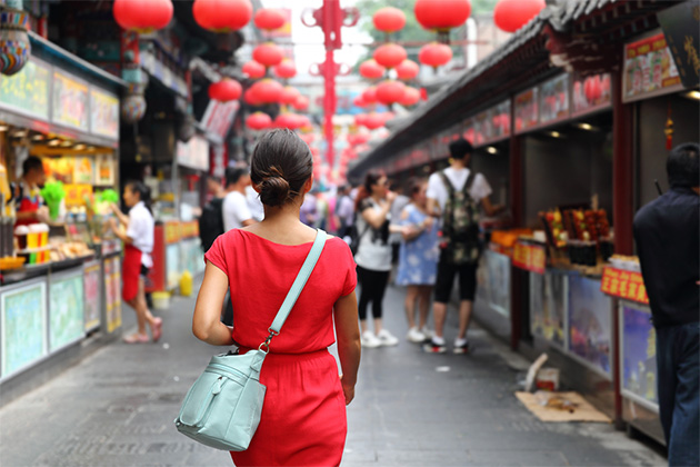 Female tourist exploring a Chinese food market (Photo: Maridav/Shutterstock.com) Woman wandering in Chinese food market