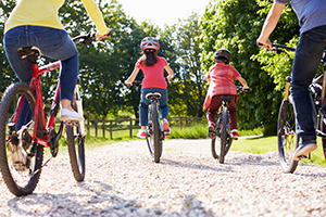 Family biking. Monkey Business Images/Shutterstock Four family members biking on gravel trail with trees in background