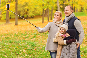 Family taking a photo with a selfie stick - photo courtesy of Syda Productions/Shutterstock family taking selfie with smartphone and monopod