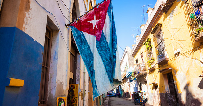 Havana, Cuba (Photo: Kamira/Shutterstock.com) Cuban flag hanging from the side of a building in Havana