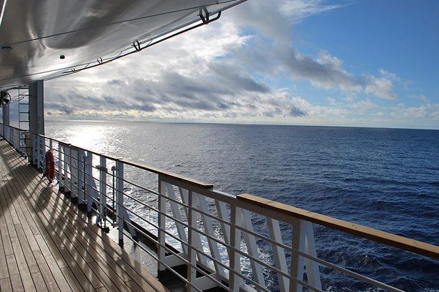 Ocean view from a cruise ship deck on a bright day with blue skies and clouds in the Pacific ocean